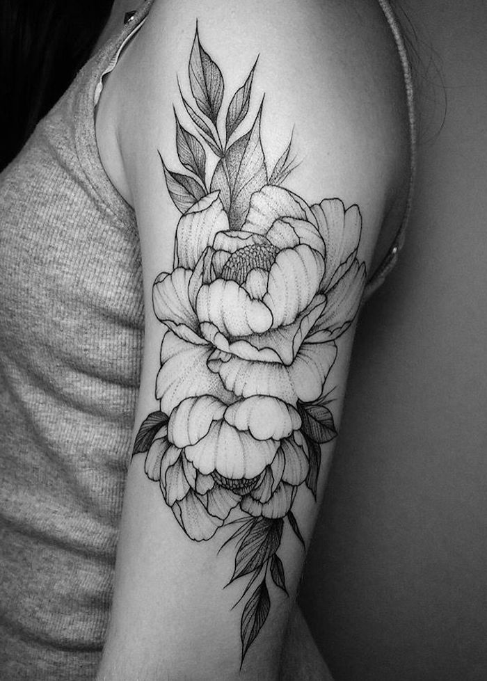 tattoo betekenis, vrouw met zwarte en grijze tatoeage op haar bovenarm