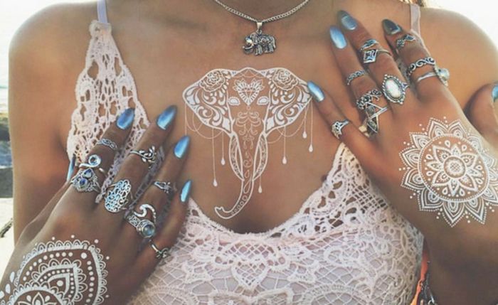 Kobieta z tatuażem henną słonia i tatuażami z dwóch mandali z białą henną, biały top z jasnej szpilki