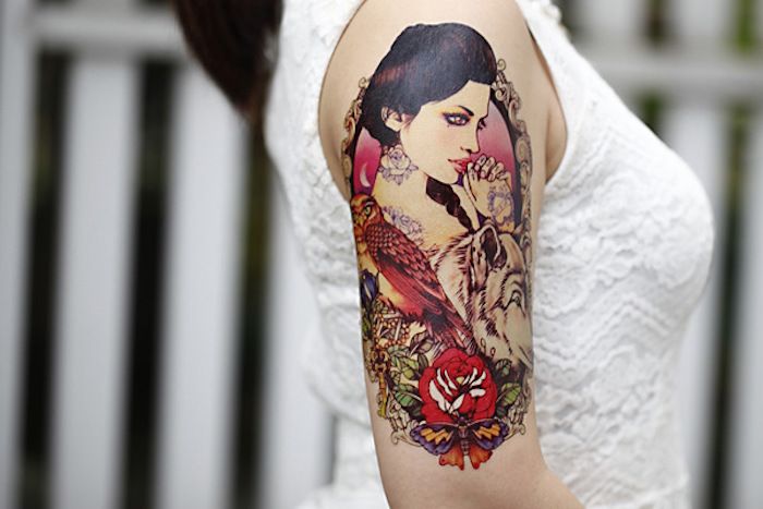 Tetovanie pre ženy, žena s bielou blúzkou s čipkou a farebné tetovanie na hornej časti paže
