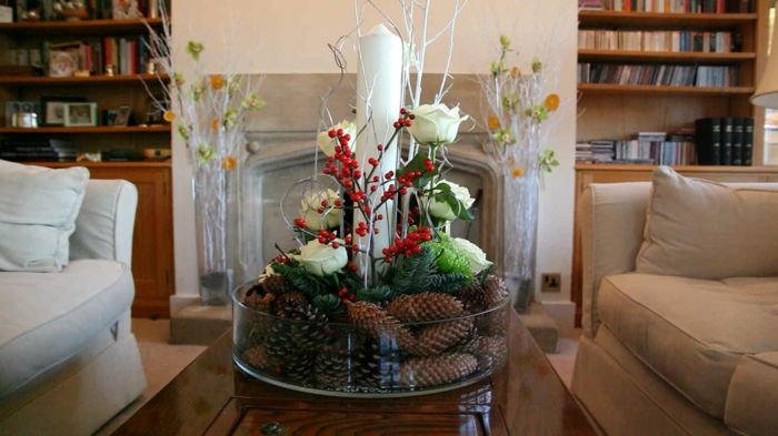 sezonska dekoracija s stožci, bele vrtnice, rdeče jagode in velika bela sveča