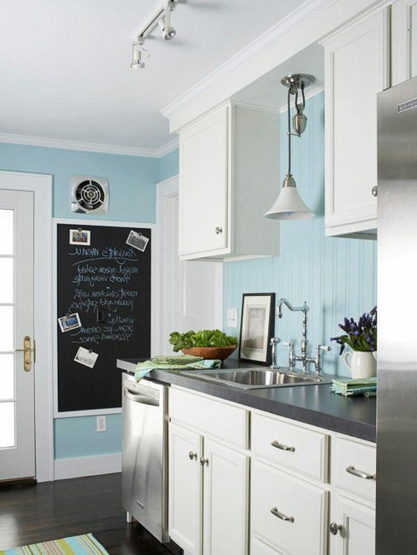 Mažoje virtuvėje baltos spalvos mėlynos sienos ir spintelės