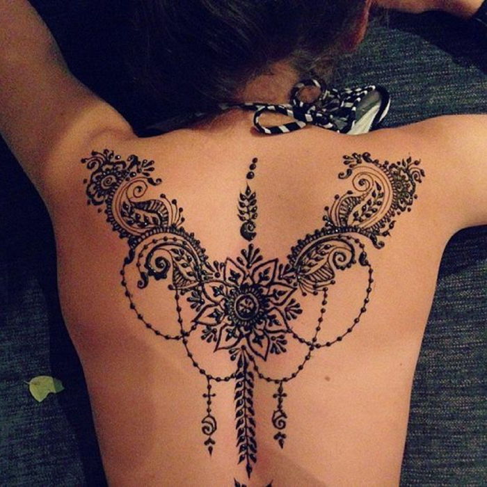 Žena s tetovanými chrbtami, čierne tetovanie mandala na chrbte, čierne a biele plavky pre ženy