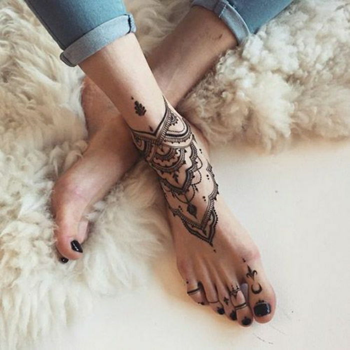 čierne členkové a prstové tetovanie, žena s džínsy a čierny lak na nechty na prstoch
