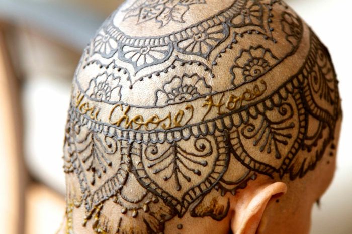 una donna con un tatuaggio testa nera di henné, lettere d'oro, motivi floreali