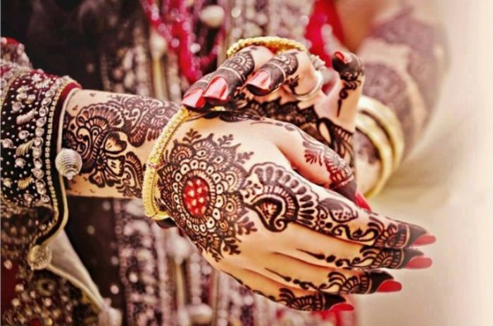 Femeie indiana cu tatuaje traditionale cu culoarea tatuajului de henna in rosu negru si rosu, lac de unghii rosii, costum indian