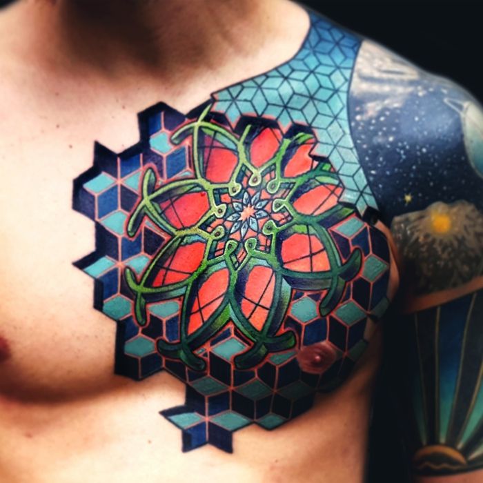 Tatuaż mandala z efektem trójwymiarowym, młody mężczyzna z kolorowym tatuażem piersiowym z motywami geometrycznymi w niebieskich kolorach. Mężczyzna z tatuażem na ramię w niebieskich kolorach