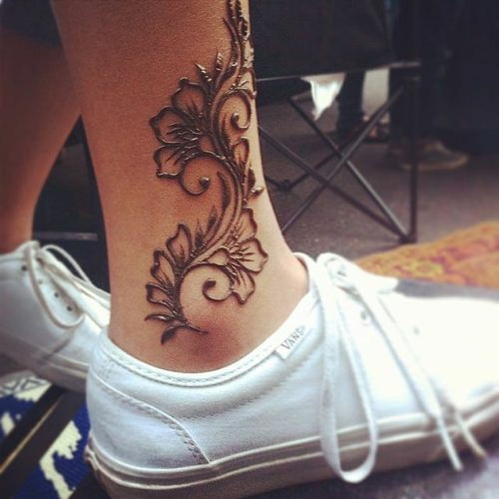 Tatuaggio all'henné color nero, tatuaggio floreale sulla gamba, ragazza con scarpe bianche VANS con tatuaggio alla caviglia