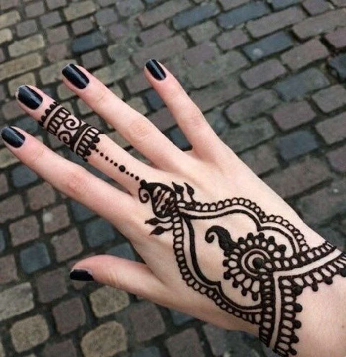 Kvinna med henna tatuering på hennes hand och på långfingeren i svart, svart nagellack