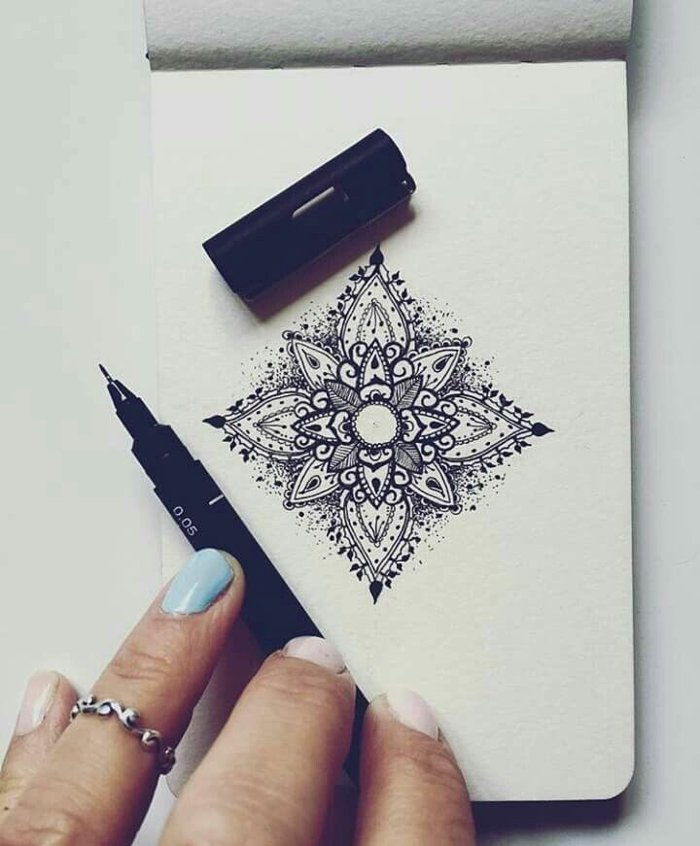 notebook mici, mandale mici în formă pătrată, creion negru, mână de femeie, unghii pictate