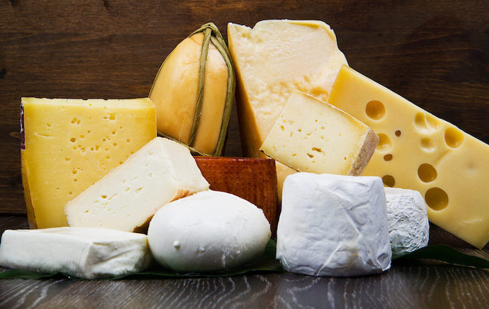 ahşap bir masa üzerinde onbir peynir, koyu renk boyalı, küçük delikli peynir, büyük delikli peynir, balmumu peyniri kabuğu, koyu kahverengi ahşap duvar