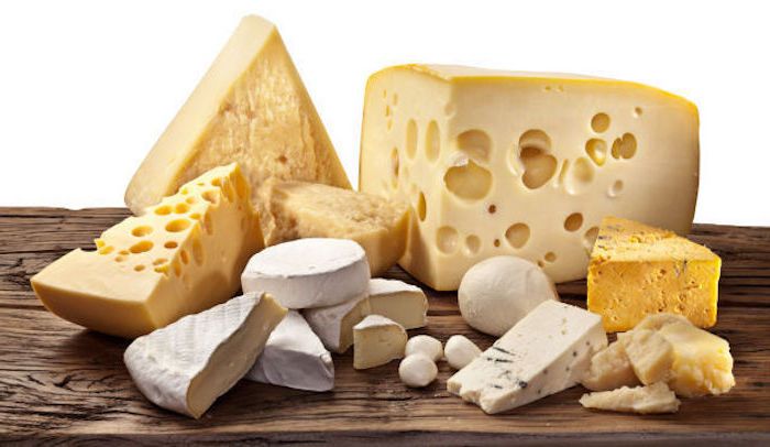 obrázok s bielym pozadím zobrazujúcim rôzne druhy tvrdého syra a syra s pružnou štruktúrou, tri lúpané prepelice vajcia vedľa parmezánu, masívny drevený stôl s veľkými trhlinami