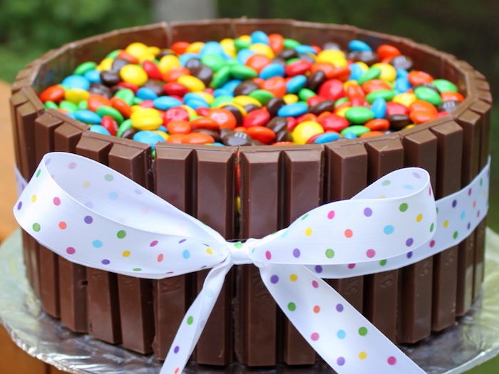 verjaardagstaart bakken, cake met kitkat versierd met kleurrijke snoepjes en strik