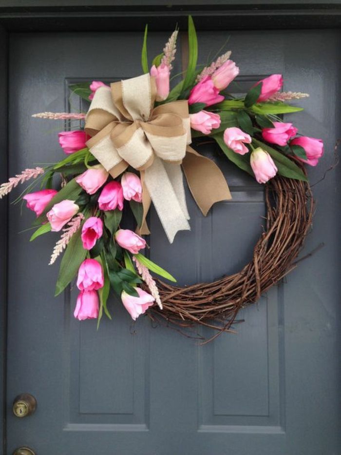 Jarná dekorácia drotár, šedé dvere. dekorácia dverí, veniec vetvičiek zdobený tulipánmi a béžový luk ľanu
