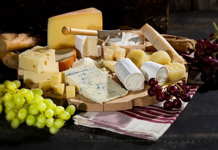 Beyaz unlu ve kepekli bagetli peynir, delikli emmental peyniri, doğrama bıçağıyla Camember, çizgili desenli kırmızı-beyaz havlu