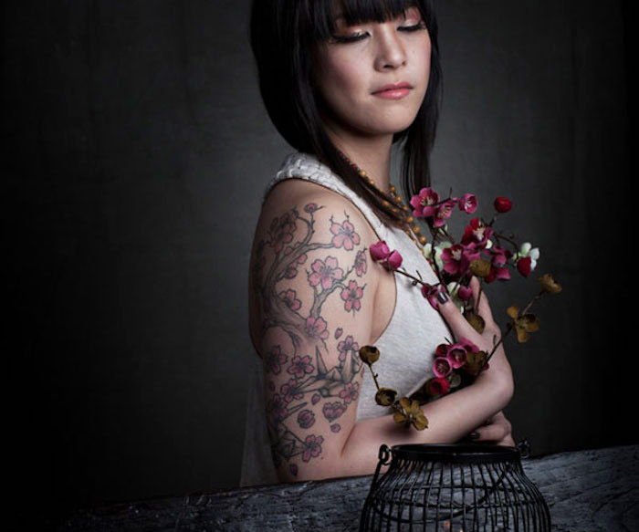 Tatuaje japoneze pentru femei, femeie cu par scurt negru și tatuaj de cireșe pentru tatuaje pe brațul ei superior