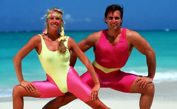 Träningsdräkt på 80-talet, leggings i neonrosa, baddräkt i gult, svettband