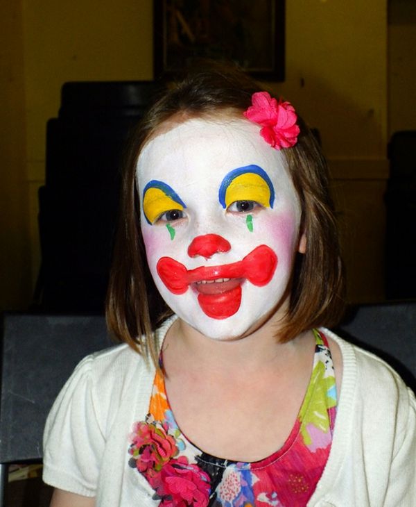 Clown ansiktsmaling - en jente ser morsom ut - med en blomst i håret hennes