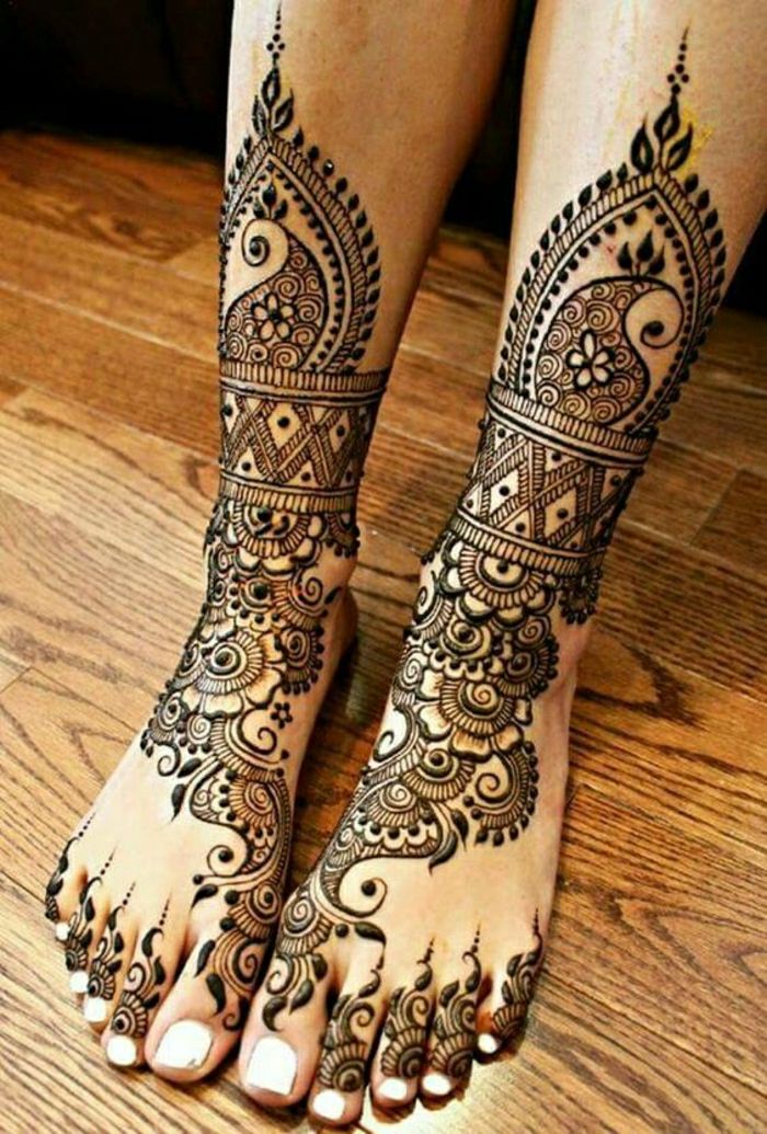 Žena s tetovanými nohami, členkami a prstami s hennou farbou, veľa ozdôb, biela lak na nechty