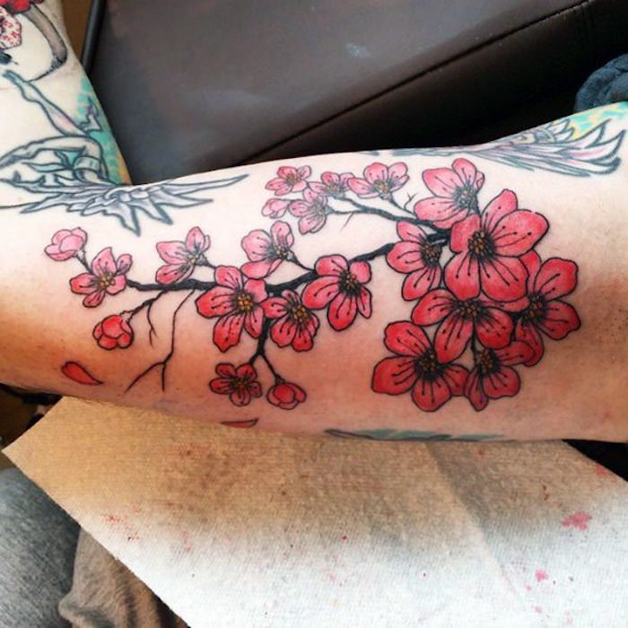 tatuaj de flori colorat pe bratul superior, ramură cu flori roșii
