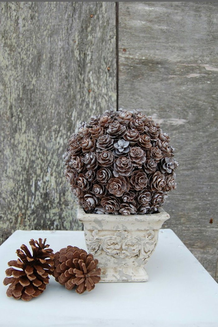 Dekorative furu kjegle-like-blomster-in-a-hvitt-vase