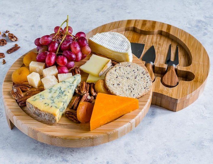 peynir bıçakları için bir dizi doğrama tahtası, kuru kayısı ve kırmızı üzüm ile mavi peynir, tohumlar ile tuz çerezleri ile cheddar, mermer mutfak masası