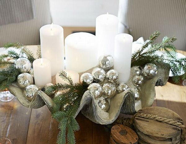 białe świąteczne dekoracje - drewniany stół z pięknymi białymi świecami na nim