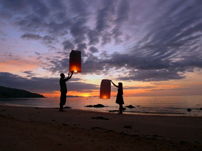 Man kvinnliga strand Sunset Flying Lanterns