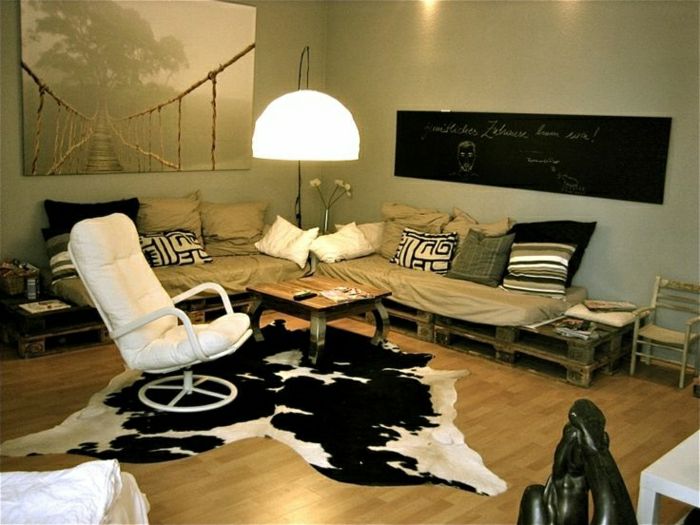 Padėklų sofa smėlio-daug pagalvės odiniai foteliai ir baltas gyvūnas odos Afrikos statula juodas ekranas didelis ekranas