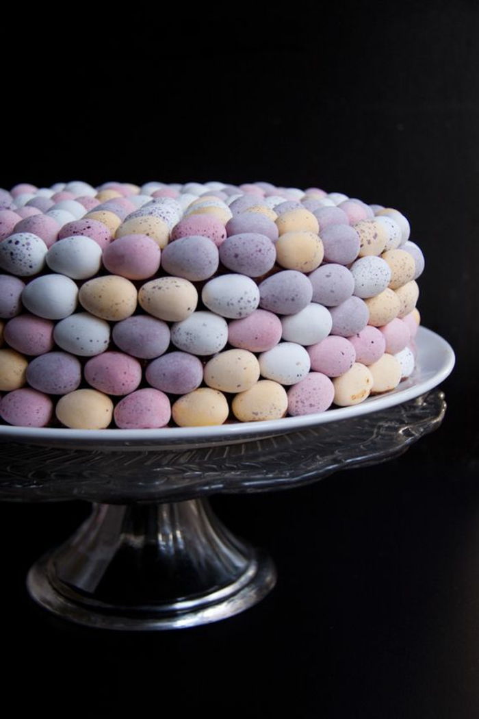 Velikonočna torta iz barvitih jajc v pastelnih barvah na stojnici s stekleno torto