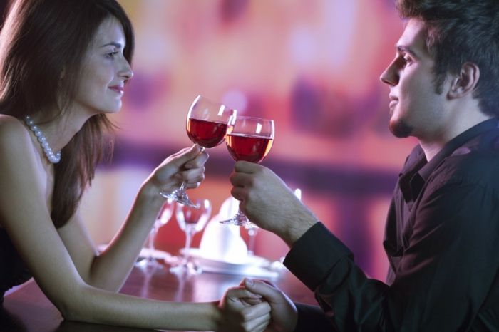 Jauna pora, kurioje restorane tiekiamas stiklinis raudonasis vynas, švenčiamas arba romantiška data