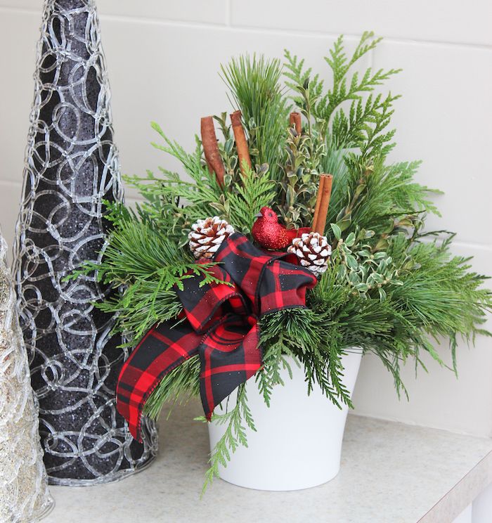 Kalėdų dekoro duris - balta vaza, raudona lankas, cinamono lazdelės