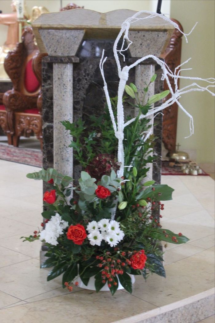 Padaryk Adventą sau - raudonos ir baltos gėlės, žalios spalvos lapai ant kamino konsolės