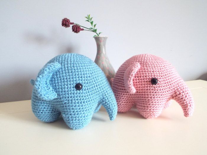 Doi elefanți mici, în culoare roz și albastru, croșesc noroc unul lângă celălalt