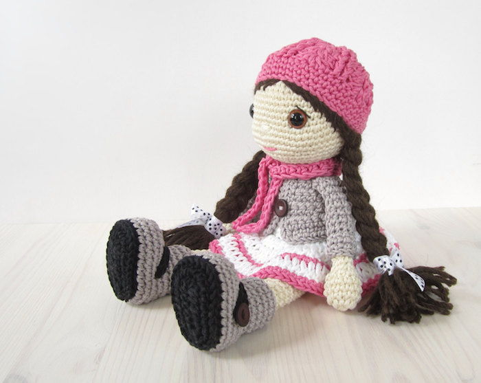 o păpușă drăguță, cu eșarfă roz și pălărie, model de croșetat amiezesc lung și maro