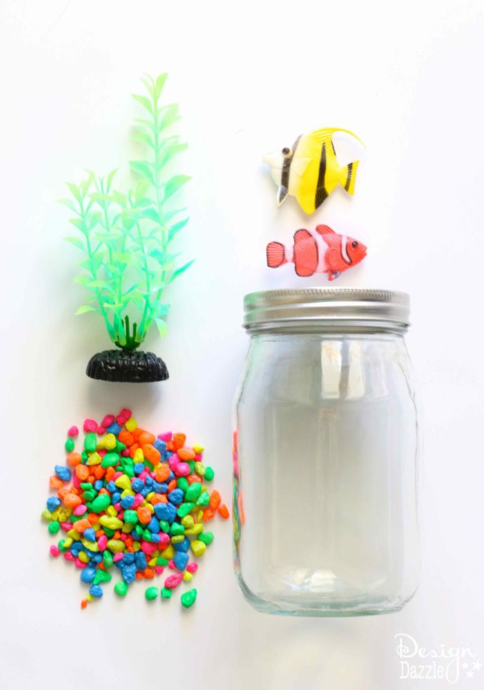 Samo akwarium, materiały: szkło, kolorowe kamienie dekoracyjne, małe ryby i plastikowy pręt morski