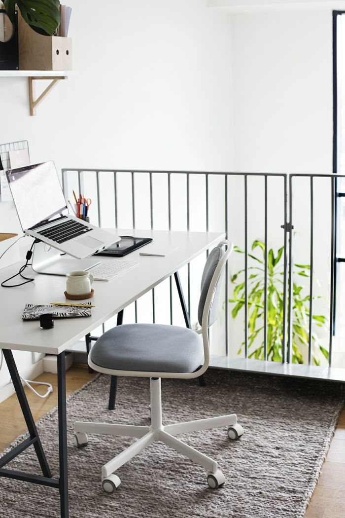 birou alb cu picioare negre, laptop, suport pentru pini și ceai pe el, covor gri