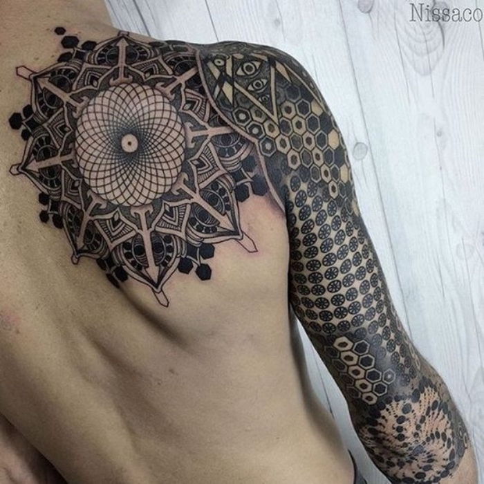 Aruncați o privire la această idee pentru un tatuaj negru mare de busolă cu motive de mandală pe scapula și pe mâna