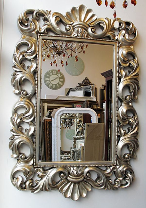 barockspegel med silverram vacker design vit vägg bakom den