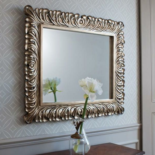 barockspegel med silverram - en vit blomma framför den