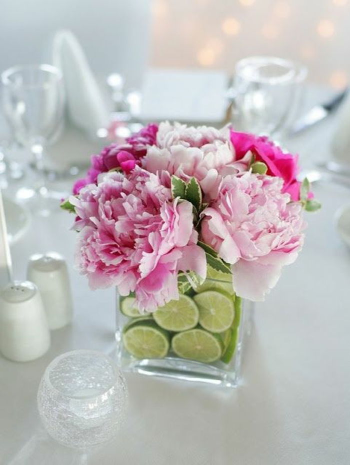 kvadrato stiklo vazos, puoštos kalkių lukštais, rausvos gėlės, stalo dekoravimas