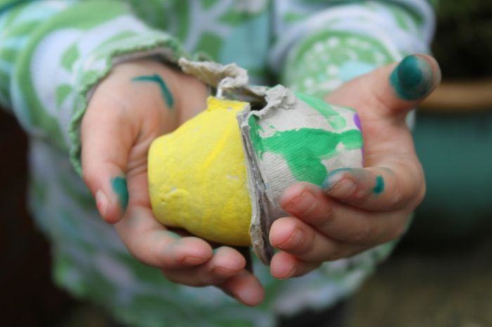 Vuile handen van kind dat twee eierdozen draagt ​​- Pasen-ambachten met eidoosje