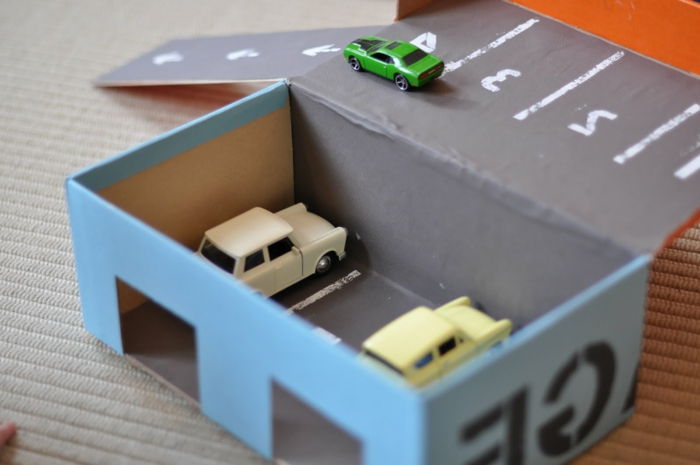 Speel auto's in de garage in blauwe kleur in twee stokken - handwerk met karton