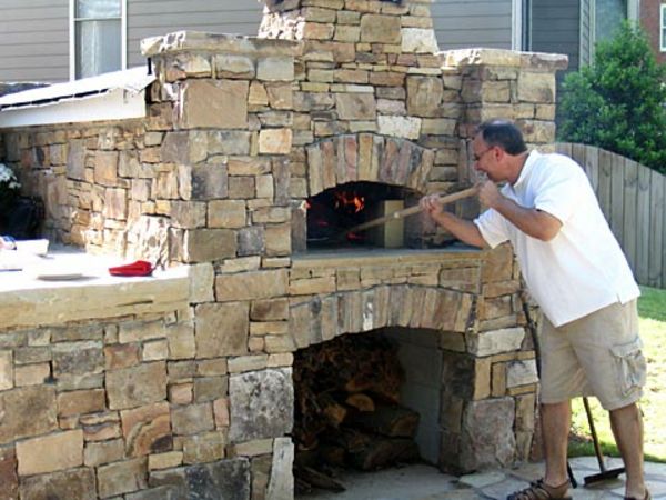 un bărbat în grădină, lângă cuptorul de pizza