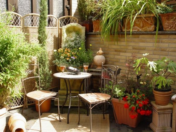 Terrasontwerp met groene planten, een ronde tafel en twee stoelen