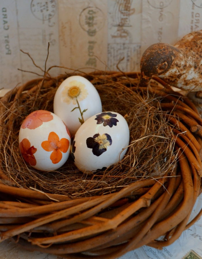 Zábavné veľkonočné vajcia maľované rôznymi kvetmi a umiestnené v hniezde