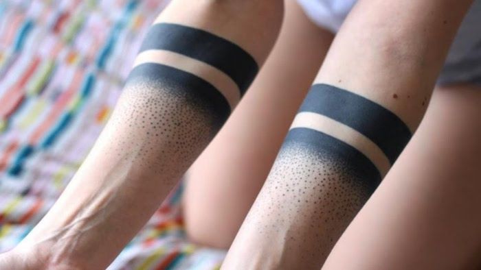 dvi juodos spalvos apyrankės. Juodoji tatuiruotė su mažomis dėmėmis ant abiejų rankų