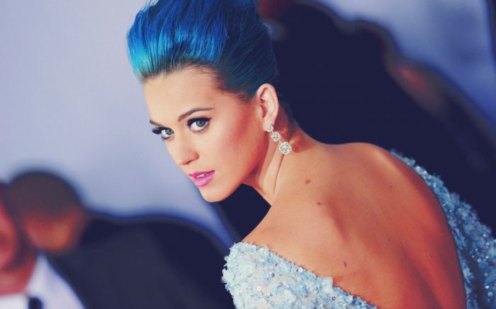 Katy Perry com cabelo azul, vestido de noite com as costas nuas, lábios roxos. brincos atraentes