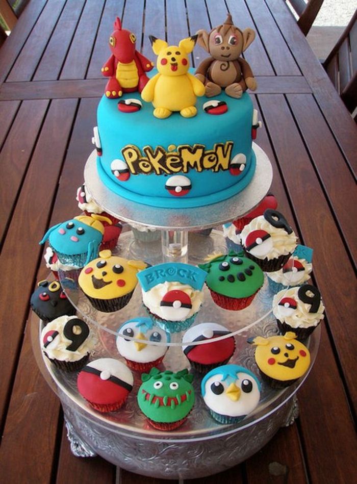 bolo de pokemon fantasia com diferente essência de pokemon e uma torta de pokemon azul com um pikachu amarelo, pokemon de dragão e manchetes amarelas