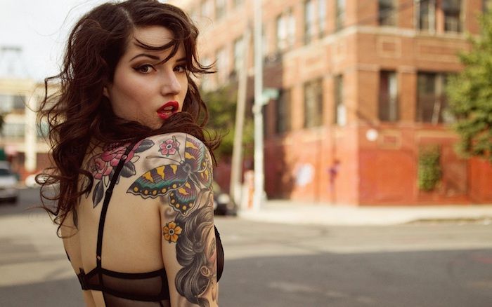 vackra tatueringar, medelålders kvinna med brunt lockigt hår och tatueringar