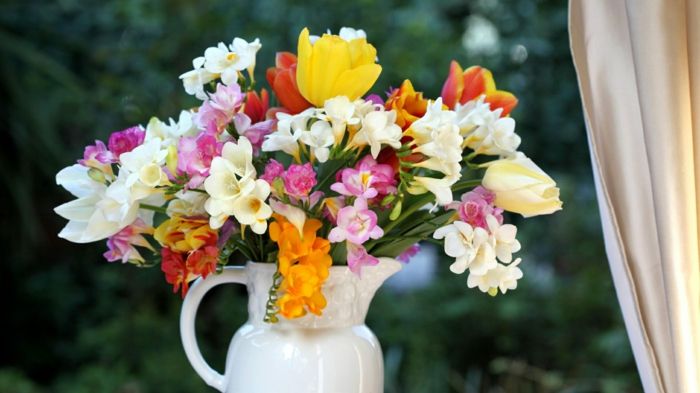 Spomladi šopek v vreči iz porcelana, barvita freesias in tulipani na oknu, ki prinašajo spomladansko razpoloženje domov